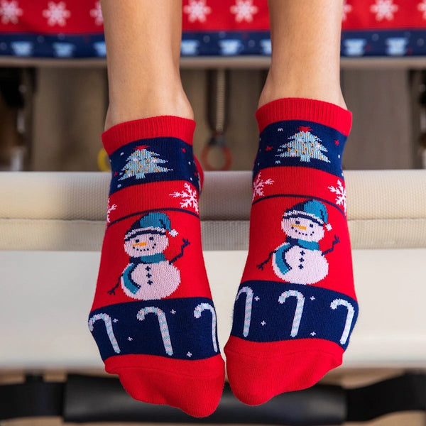 Red and blue Christmas-themed socks with snowmen and candy canes on a white surface.