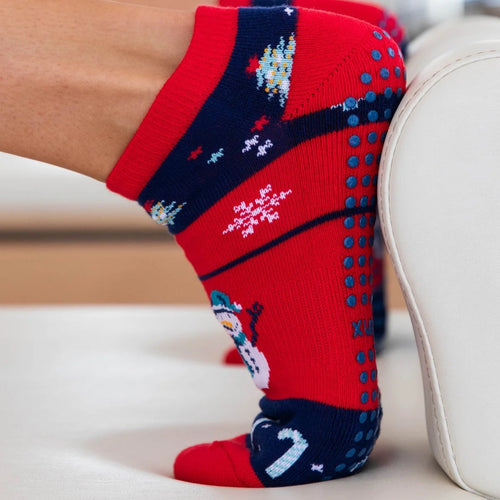 Red and blue patterned socks worn by a person sitting on a white couch.