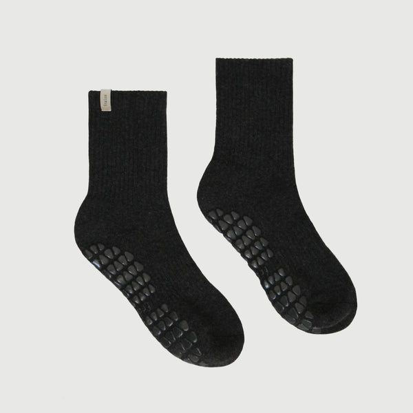 Pair of black socks with textured sole on a light gray background