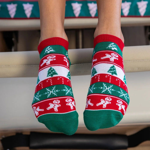 Person wearing festive red and green socks with gingerbread men design on a staircase.