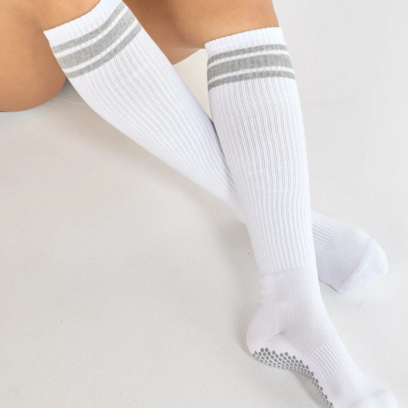 White knee-high socks with gray stripes worn by a person on a light background