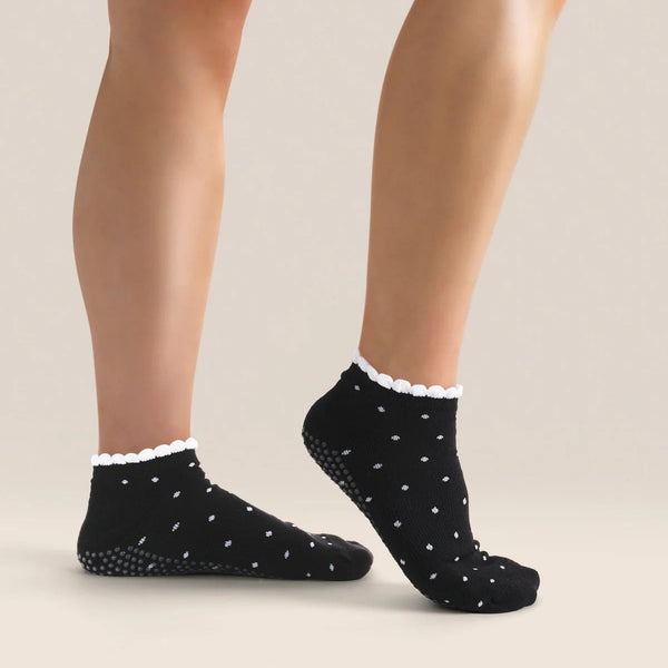 Black socks with white polka dots worn by a person on a beige background