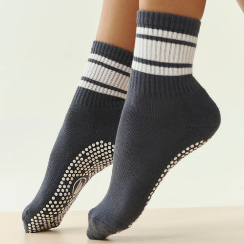 Pair of dark navy socks with white stripes and textured sole on a light background