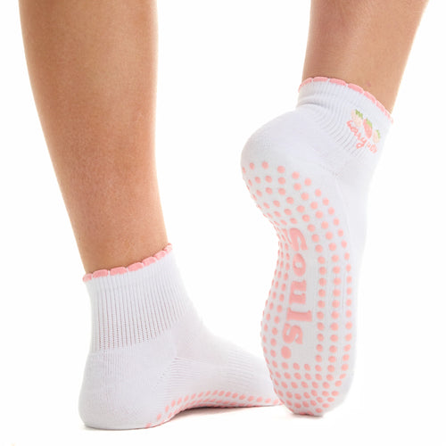 White socks with pink grip dots worn by a person on a white background