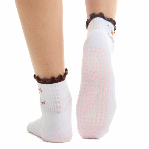 White socks with pink polka dots and brown accents worn by a person on a white background