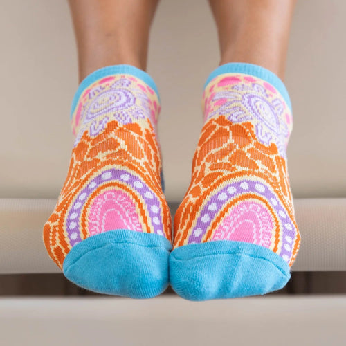 Colorful patterned socks with blue toes worn by a person on a neutral background