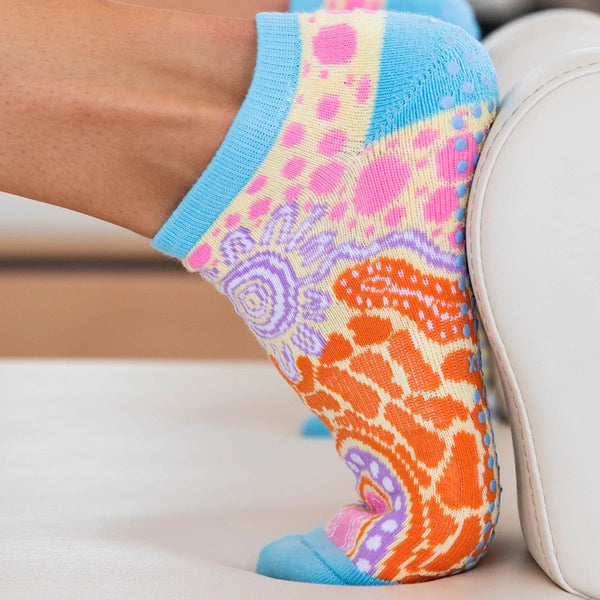 Colorful patterned socks with blue trim worn by a person sitting on a couch.