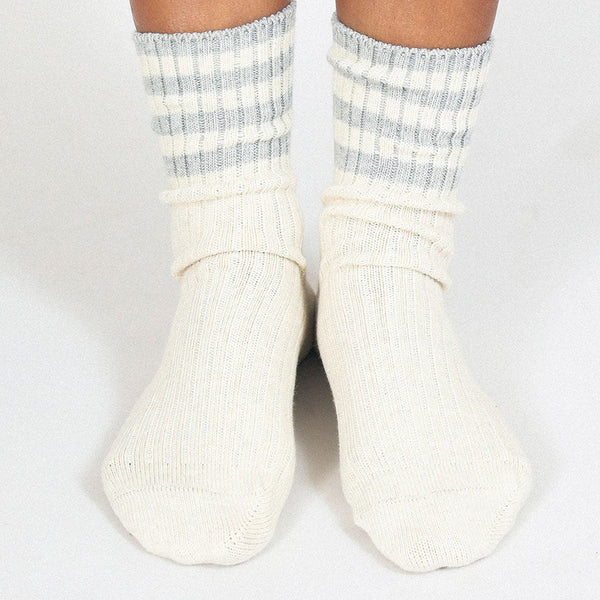White socks with gray stripes worn by a person on a white background