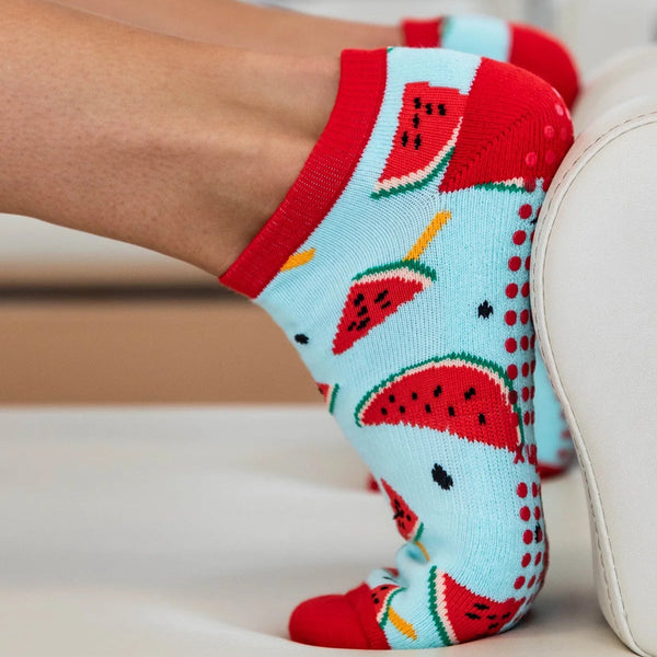 Blue socks with watermelon design worn by a person sitting on a couch.
