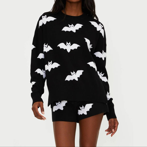 Woman wearing a black sweater and shorts set with white bat patterns on a light gray background