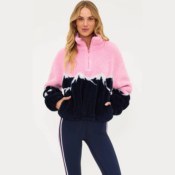 Person wearing a pink and black tie-dye fleece pullover with navy pants on a white background