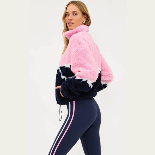 Woman wearing a pink and navy fleece jacket with matching leggings on a white background