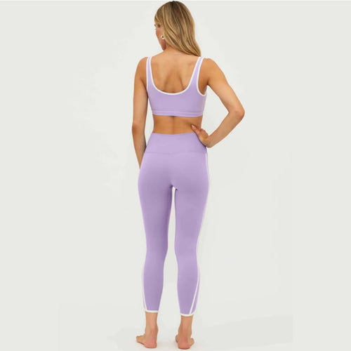 Woman wearing a purple sports bra and leggings set on a white background