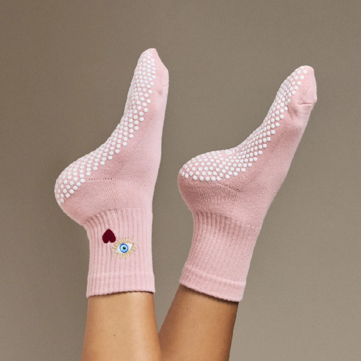 Pink socks with grip dots on a plain background