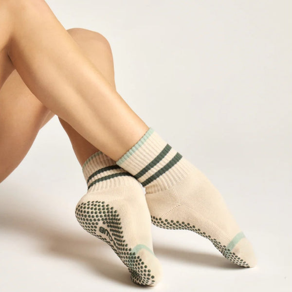 Beige socks with green accents worn by a person on a light gray background