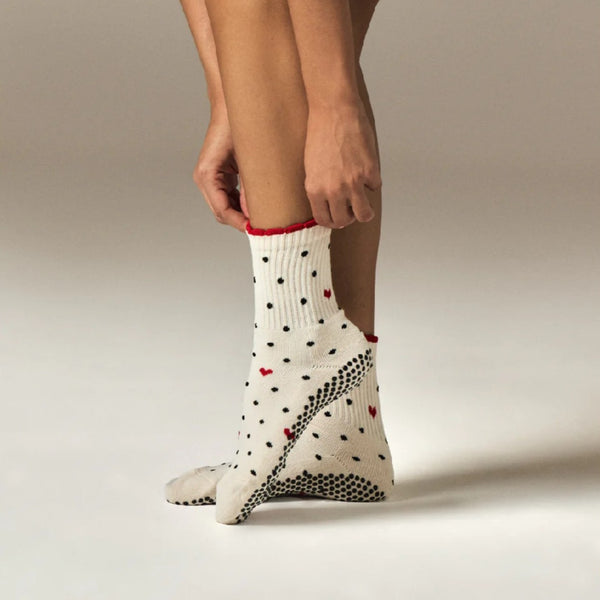 White sock with black and red patterns being worn by a person on a neutral background