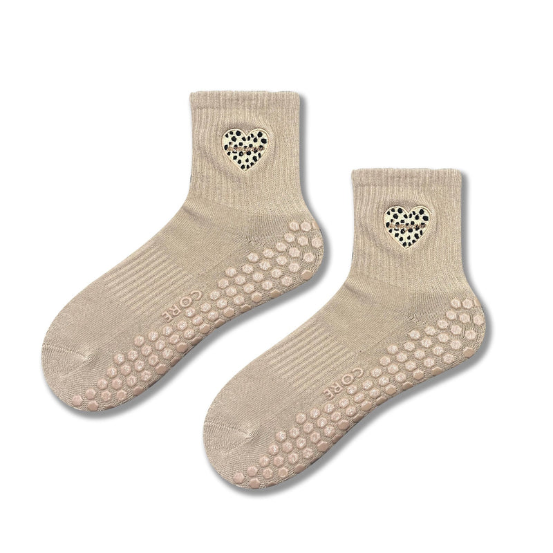 Pair of beige socks with heart designs and non-slip sole on a white background