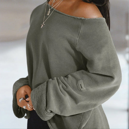 Woman wearing a green off-shoulder sweater with a blurred background