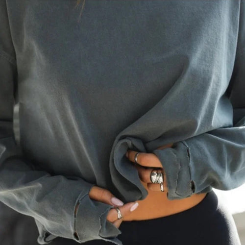 Person wearing a gray oversized sweatshirt with hands in pockets.
