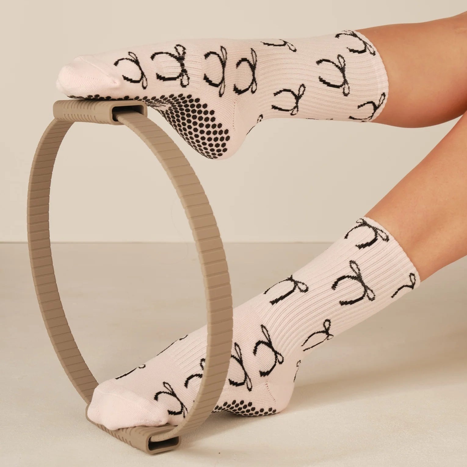 Person wearing light pink socks with black patterns on a beige background