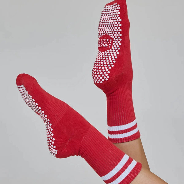 Red socks with white grip dots and stripes on a gray background