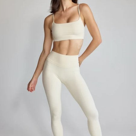 Person wearing a beige sports bra and leggings on a plain background