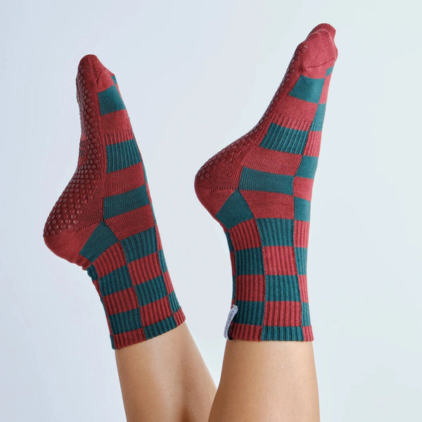 Red and green checkered socks worn by a person on a light gray background