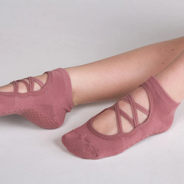 Pink ballet-style socks worn by a person on a light gray background