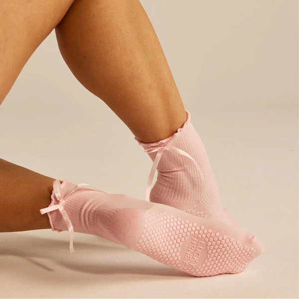 Pink slip-on grip socks worn by a person on a neutral background