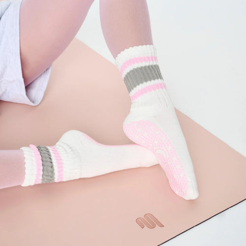 White socks with pink and gray stripes worn by a person on a light background