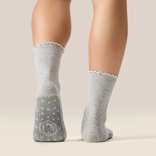 Gray socks with textured sole and lace trim worn by a person on a beige background