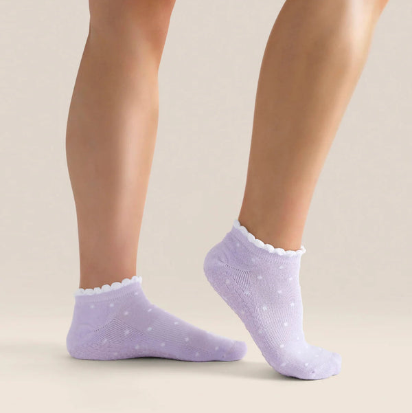 Purple socks with white polka dots worn by a person on a beige background
