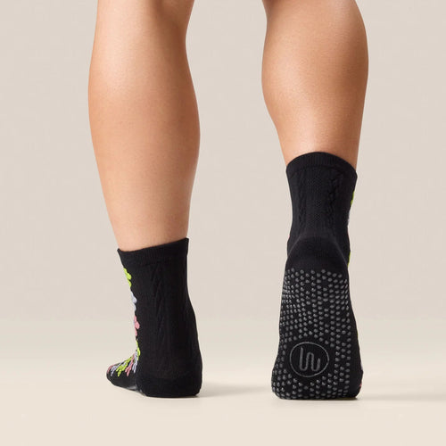 Black socks with textured sole worn by a person on a neutral background