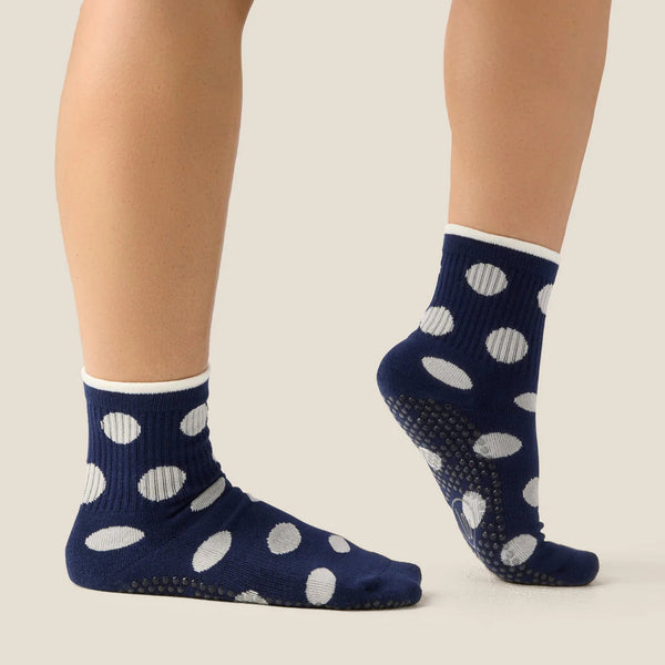 Navy blue socks with white polka dots worn by a person on a light background