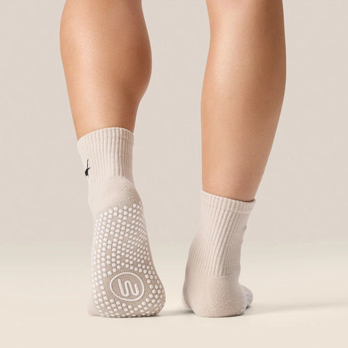 White socks with textured sole worn by a person on a neutral background