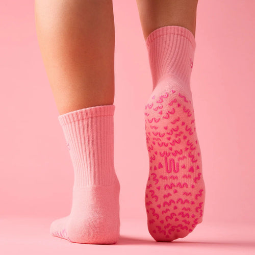 Pink socks with textured sole on a pink background