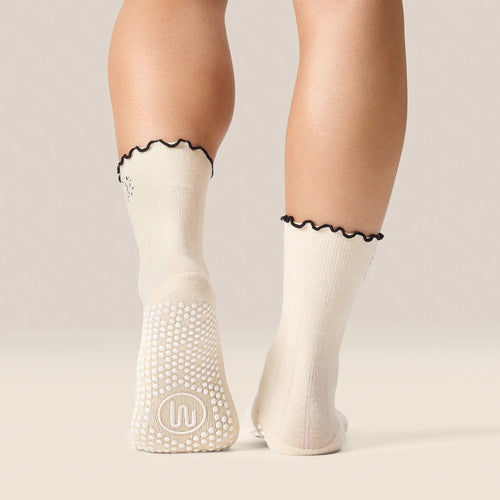 White socks with black trim and textured sole on a neutral background