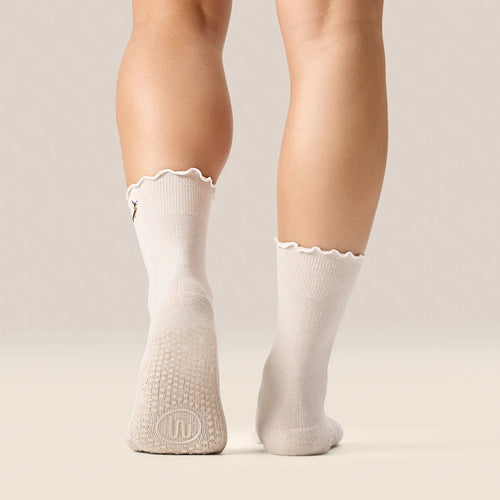 White socks with scalloped edges worn by a person on a beige background