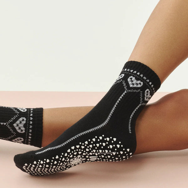 Black socks with white patterns worn by a person on a beige background
