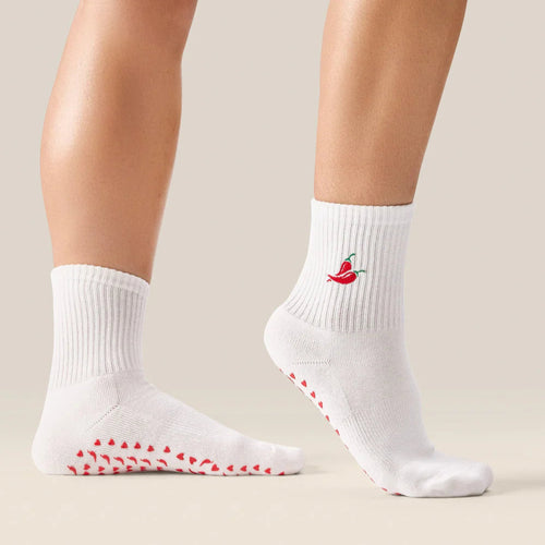 White socks with red slip-resistant sole and chili pepper design on a neutral background