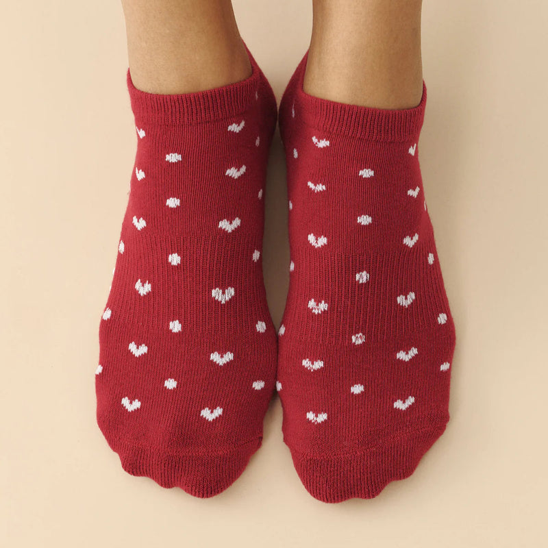 Red socks with white patterns worn by a person on a beige background