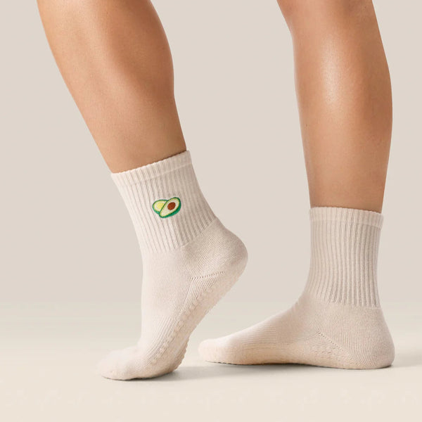White socks with avocado design worn by a person on a neutral background