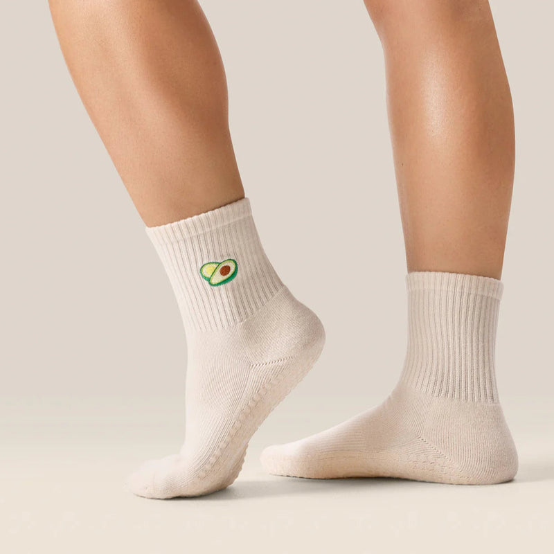 White socks with avocado design worn by a person on a neutral background