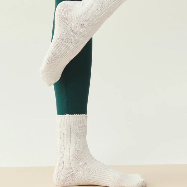 White socks worn with green leggings on a neutral background