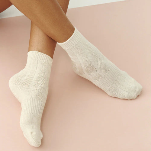 White socks worn by a person on a pink surface