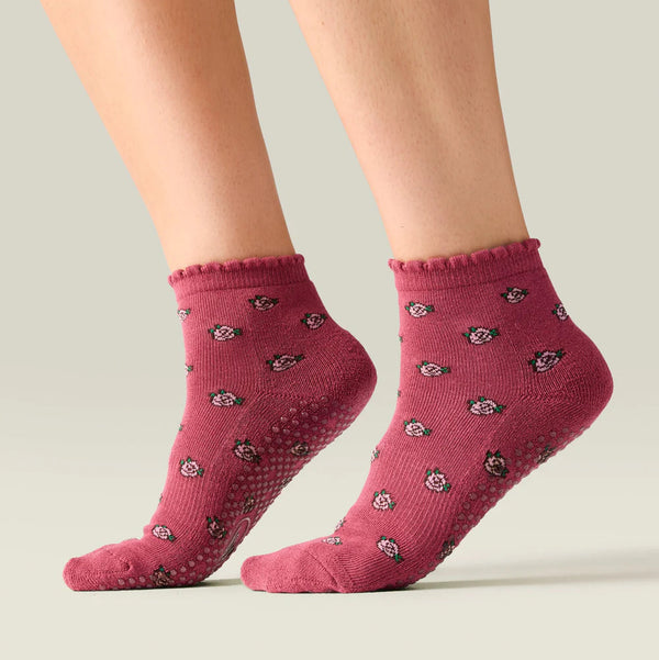 Pink socks with black patterns worn by a person on a light gray background