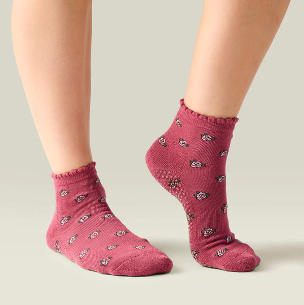 Pink socks with small black patterns worn by a person on a neutral background