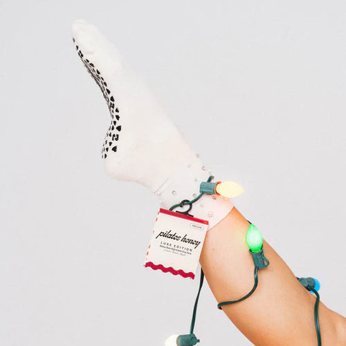 Person wearing white socks with a string of lights attached, on a plain background
