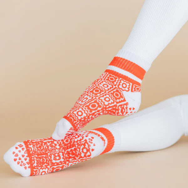 Orange patterned socks worn on a beige background