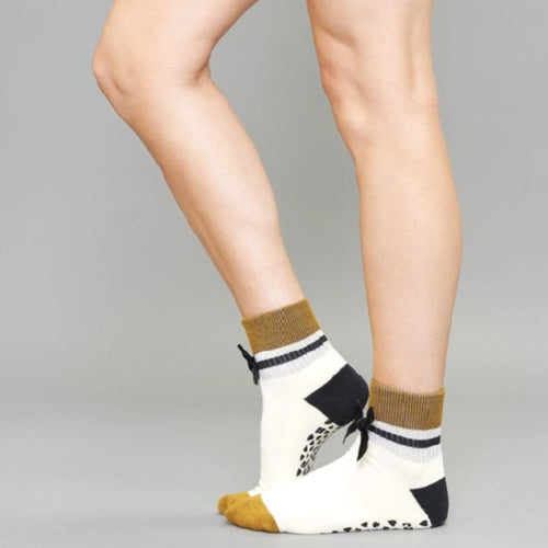 Person wearing socks with a bow design on a gray background